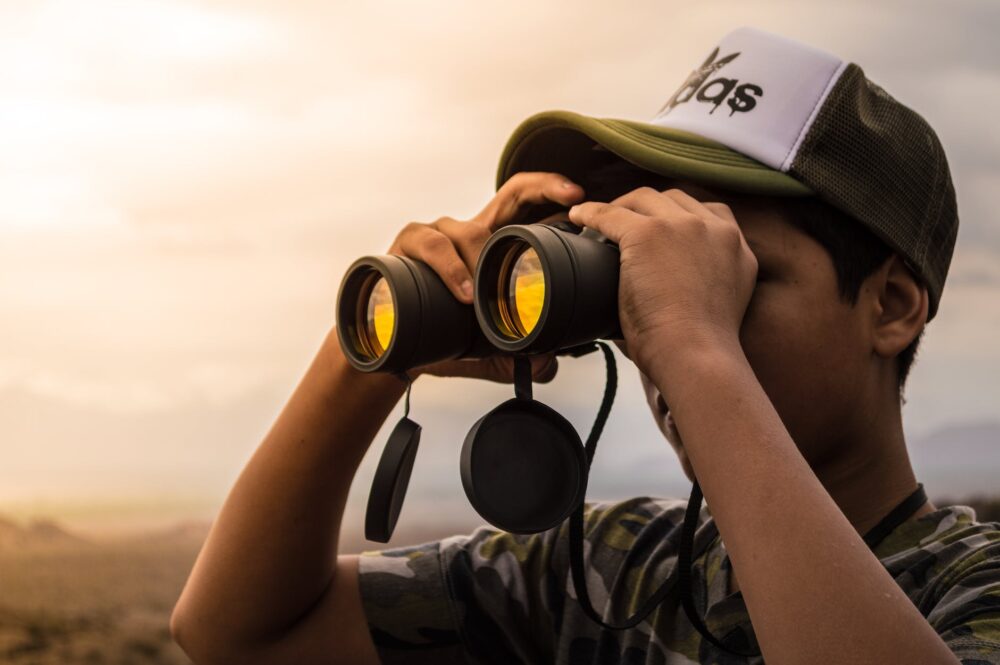man looking in binoculars during sunset