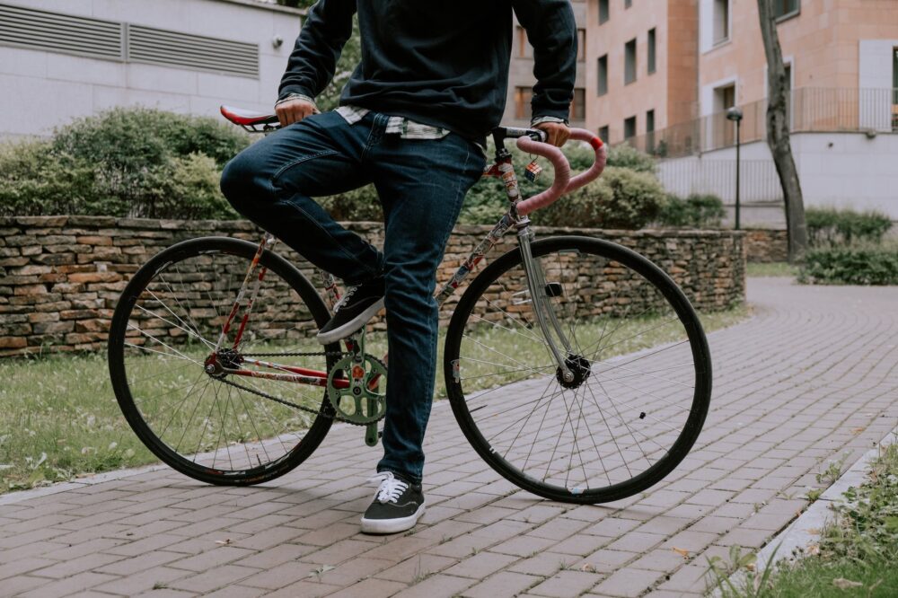 person in blue denim jeans and black jacket riding on pink bicycle